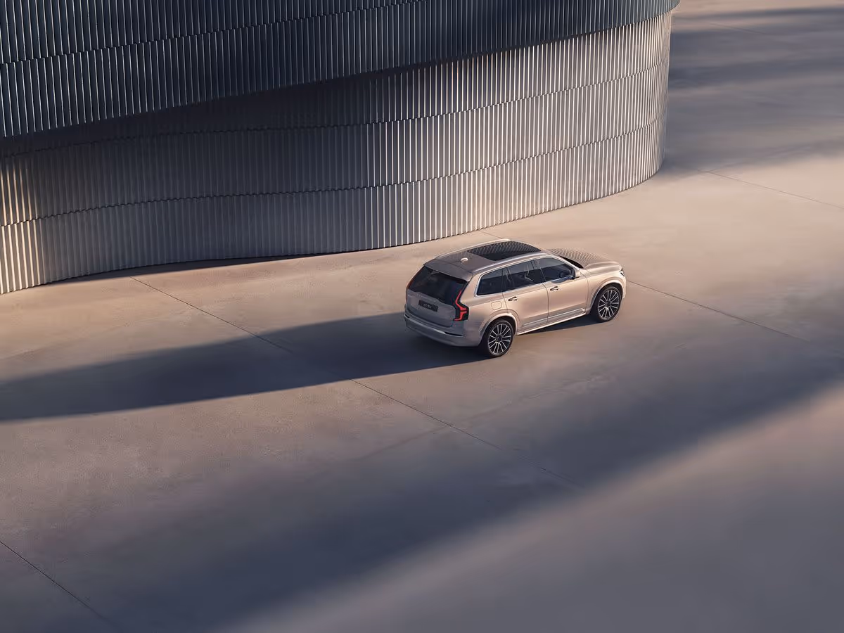 Silver SUV parked on a smooth concrete surface near a curved, vertically ribbed metal wall.
