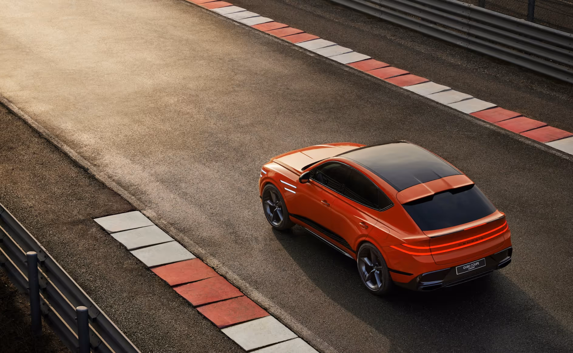 Red luxury coupe SUV with tinted windows on a race track with red and white curbs.