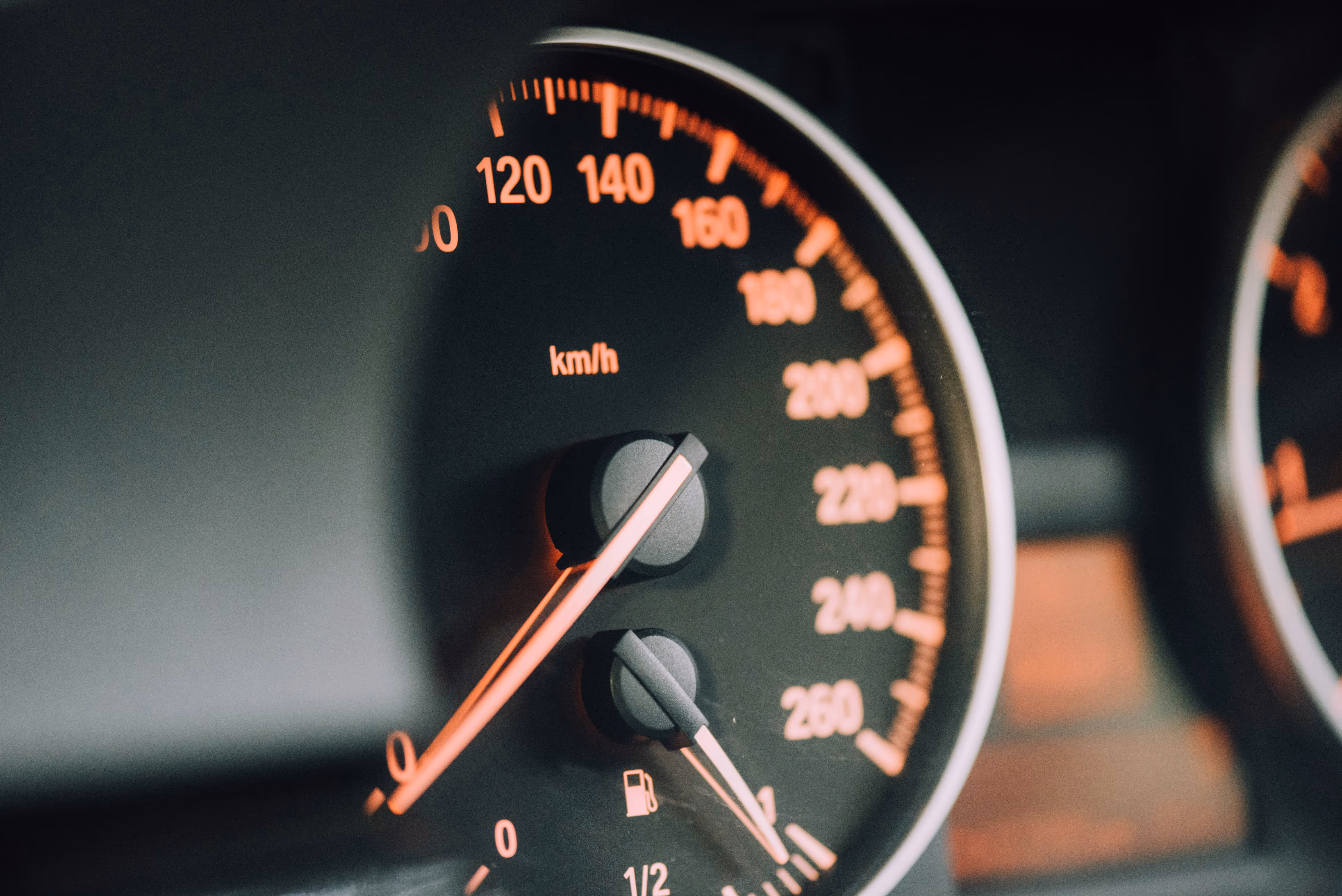 Close-up of a car speedometer showing 0 km/h and fuel gauge near full.