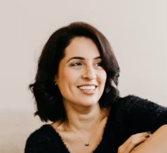 Smiling woman with short dark hair wearing a black top against a plain light background.