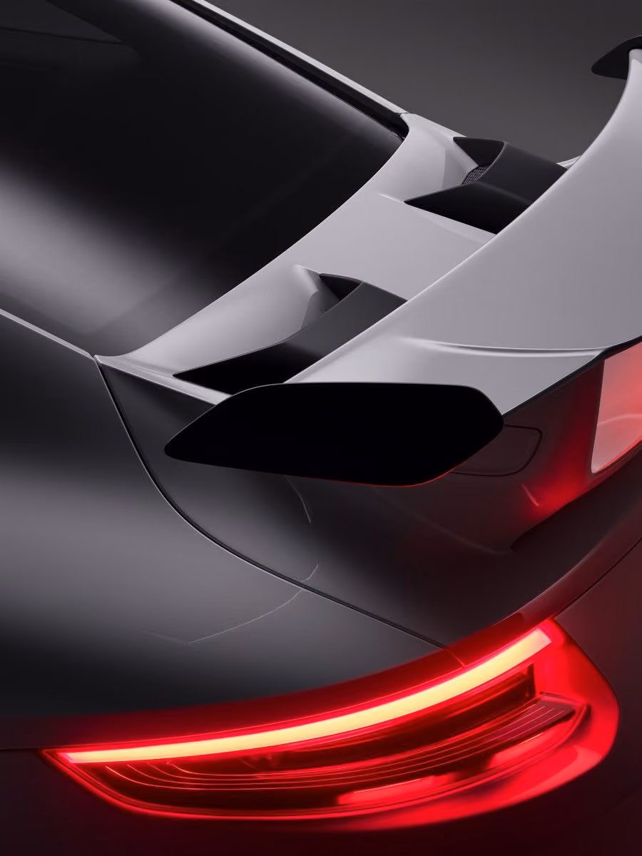 Close-up of a car's rear wing spoiler with illuminated red taillight.