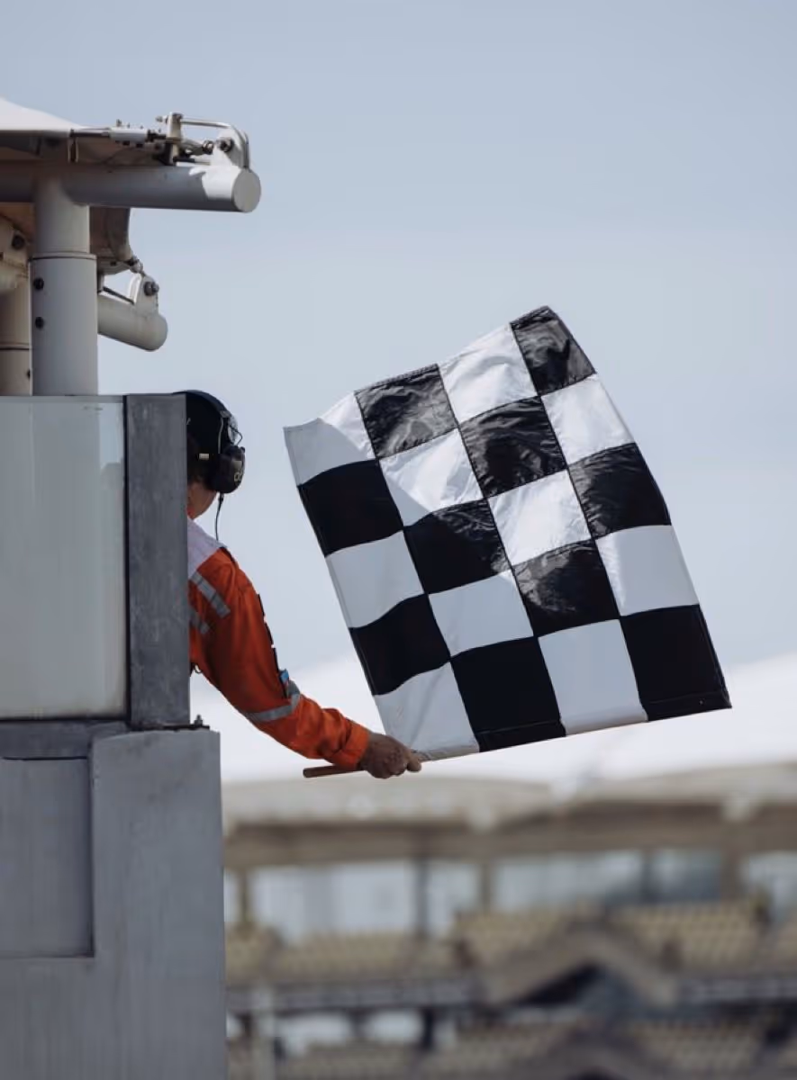 Race official waving a black and white checkered flag signaling the end of a race.