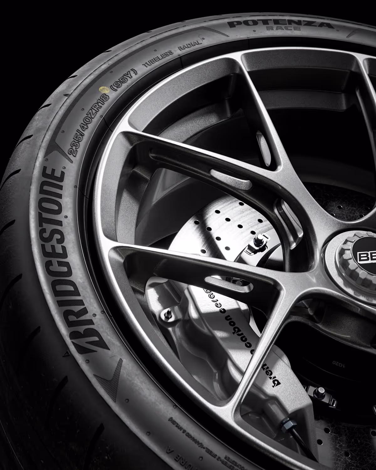 Close-up of a Bridgestone Potenza high-performance car tire mounted on a metallic alloy wheel with a visible brake caliper and perforated brake disc.