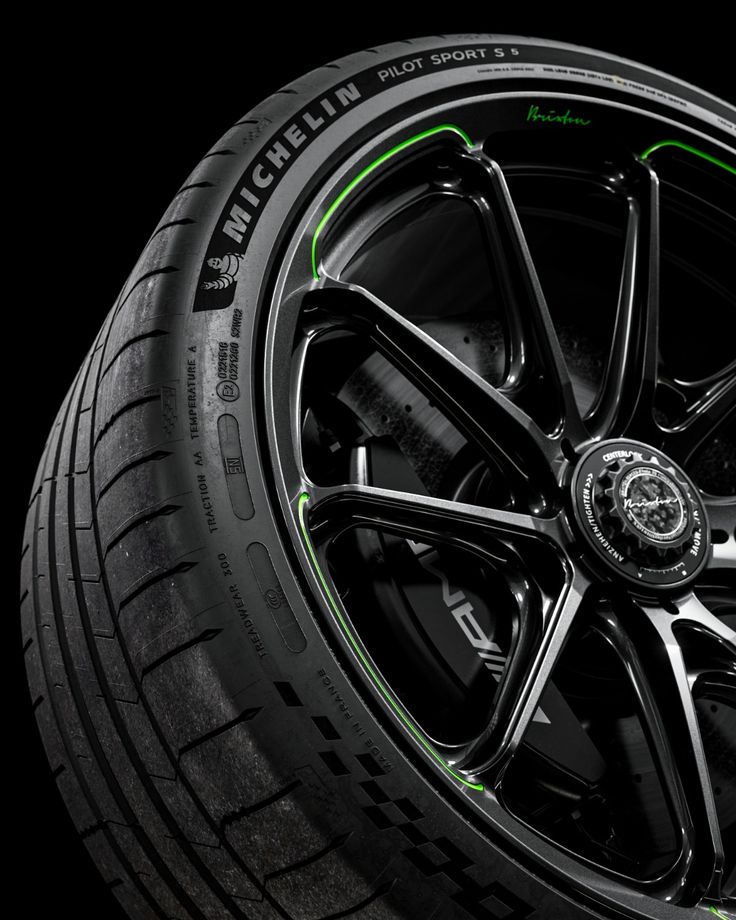 Close-up of a Michelin Pilot Sport 5 tire mounted on a black multi-spoke alloy wheel with green accents.