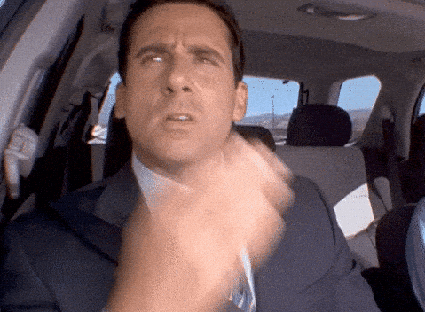 Man in a car making a confused or thoughtful facial expression while moving his hand near his face.