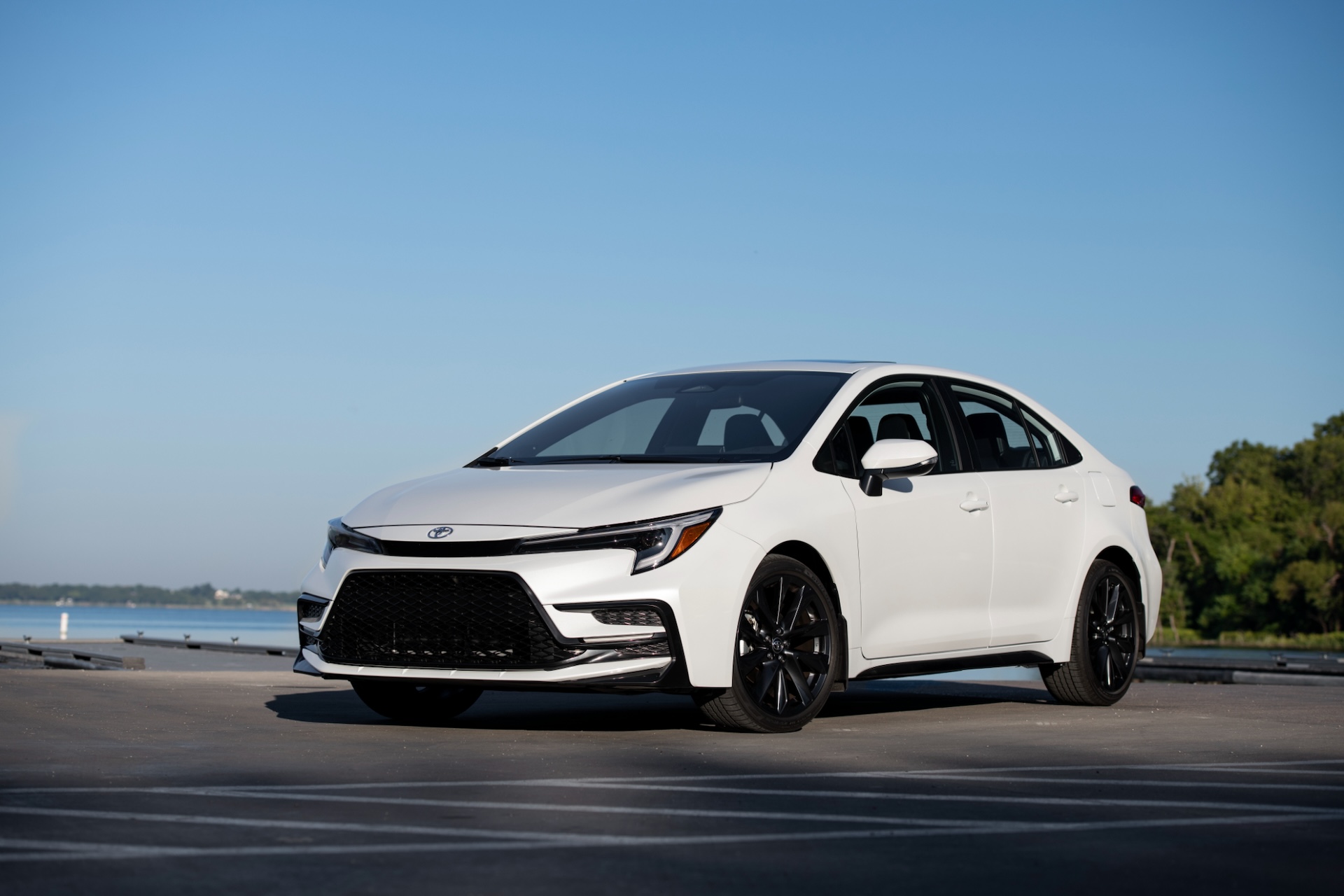 White 2025 Toyota Corolla LE parked outdoors near a body of water under clear blue sky.