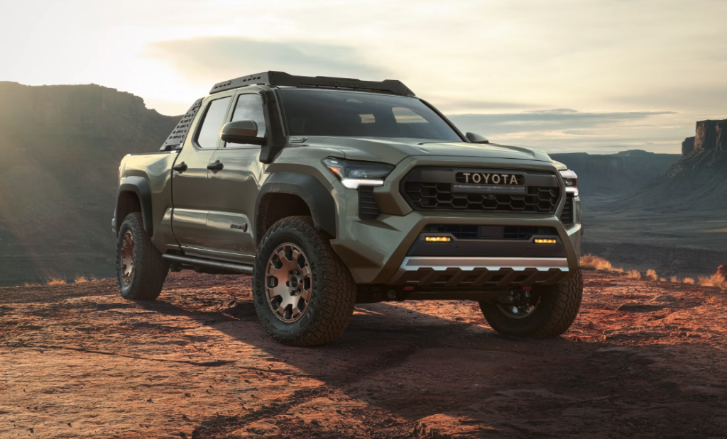 Toyota pickup truck parked on rocky terrain at sunset with mountains in the background.