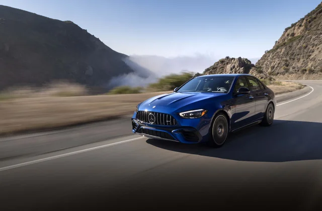 Blue Mercedes-AMG C63S E-Performance driving on a winding mountain road during daytime.